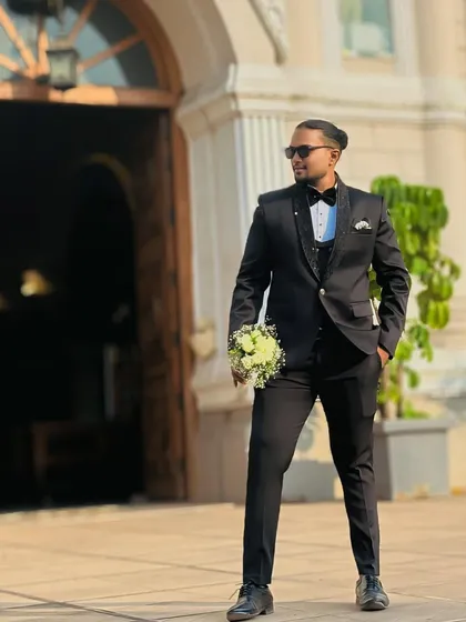 Ready for the ceremony. This groom looks handsome and ready to meet his bride, holding a bouquet while wearing a classic black tuxedo.