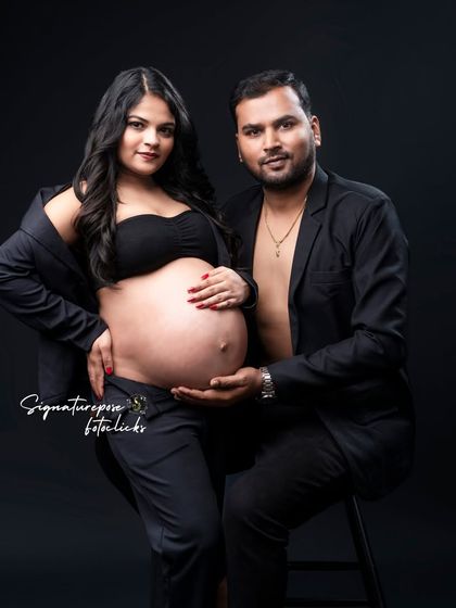 A confident couple's portrait in matching black outfits, looking directly at the camera with a powerful presence.