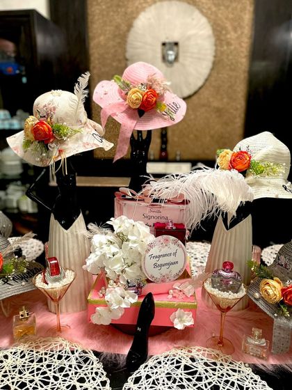 This shot showcases the creative use of props in the perfume paradise theme. Decorated hats on stands, gift boxes, and perfume bottles are arranged to create a visually interesting and fragrant tablescape.