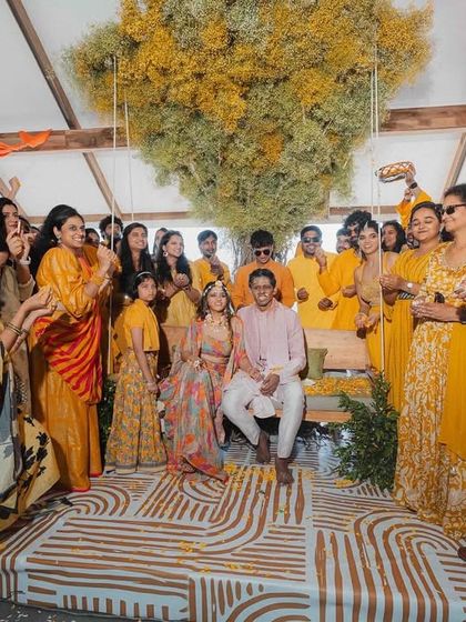 A candid moment from the Haldi ceremony, showing the couple surrounded by their loved ones. The decor, with the tree of yellow baby's breath, provided a stunning and memorable backdrop for their celebration.