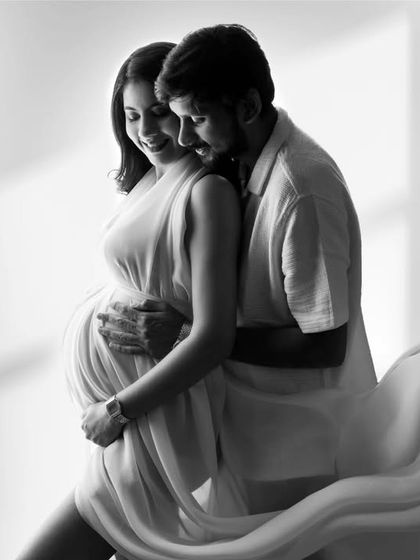 A timeless black and white photo of the couple. The soft light from the window and the flowing fabric of her gown create a romantic, classic feel that they will cherish forever.