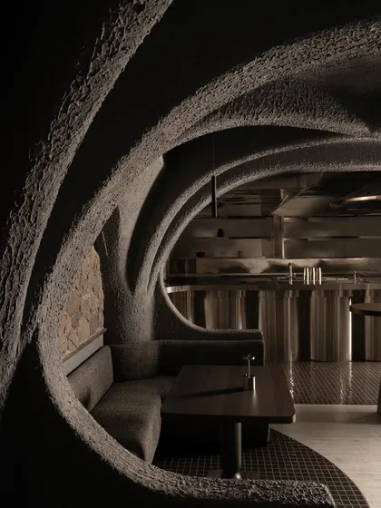 This is a view into the heart of Call Me Ten, a Japanese-inspired restaurant in New Delhi. The design is a study in brutalist poetry, where repeating concrete arches create a rhythmic, cave-like procession, guiding the eye and the body through a narrative of shadow and form.