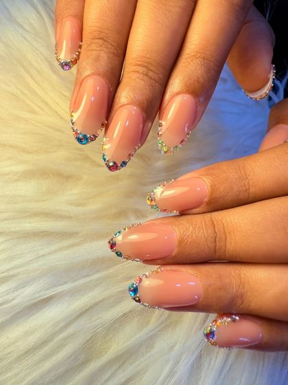 A full view of the rainbow crystal manicure. The colorful stones create a beautiful, sparkling frame around the natural nail, offering a unique and glamorous look.