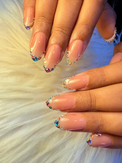 A full view of the rainbow crystal manicure. The colorful stones create a beautiful, sparkling frame around the natural nail, offering a unique and glamorous look.