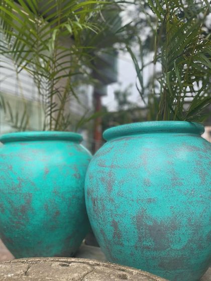 A pair of my antique-finish teal planters, perfect for adding a vibrant splash of color to your garden.