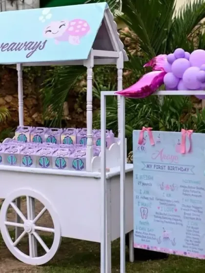 Another view of the adorable giveaway cart, perfectly integrated with the sea-themed balloon decor and a milestone board for the birthday girl.