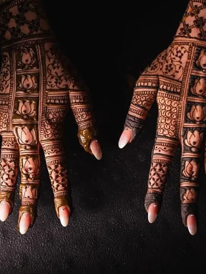 A close-up of the intricate lotus patterns on the fingers of a bridal mehendi design.