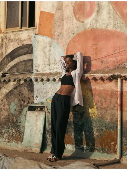Using a colorful, textured wall as a backdrop, this shot blends urban art with fashion. The model's relaxed pose and the strong shadows create a cool, street-style vibe.