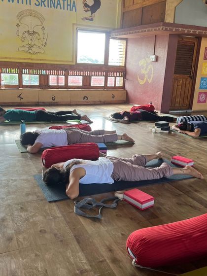 Students rest in a supported prone twist, a gentle and effective way to release tension in the spine and internal organs.