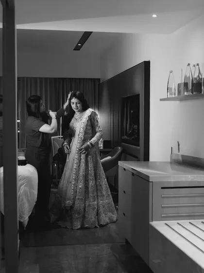 A black and white behind-the-scenes shot of the bride getting ready.
