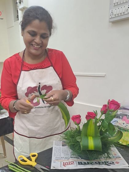 A smile of accomplishment from a student in Class 1. She is learning to manipulate leaves and place stems to create a balanced and beautiful foundational floral arrangement.