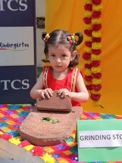 Celebrating the vibrant festival of Baisakhi. This little girl, dressed in colourful ethnic wear, tries her hand at a traditional grinding stone, connecting with the harvest festival's cultural roots.