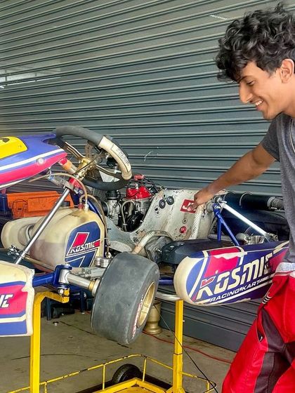 A driver inspects his Kosmic kart with a mechanic, learning the ins and outs of his machine.