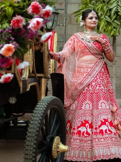 This bride looks like she stepped out of a fairytale, posing next to a floral carriage in her stunning red lehenga.