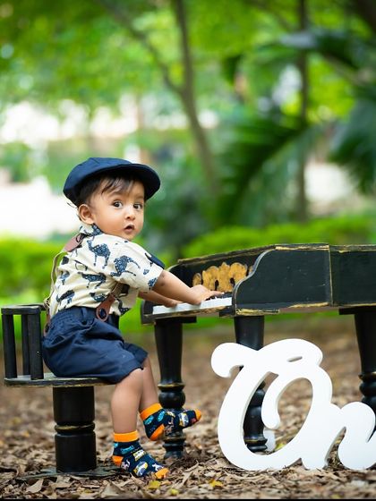 Taking the piano outdoors for a unique first birthday photo. The contrast between the formal prop and the natural setting creates a striking image.