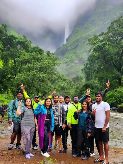 A happy group photo from the Kalu river trek, with the famous waterfall visible in the misty background.