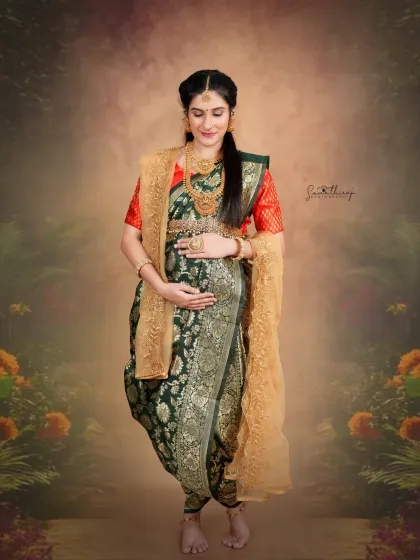 A beautiful solo portrait of a mother-to-be in a traditional green saree. The soft, painterly background and her serene expression create a timeless and artistic image.