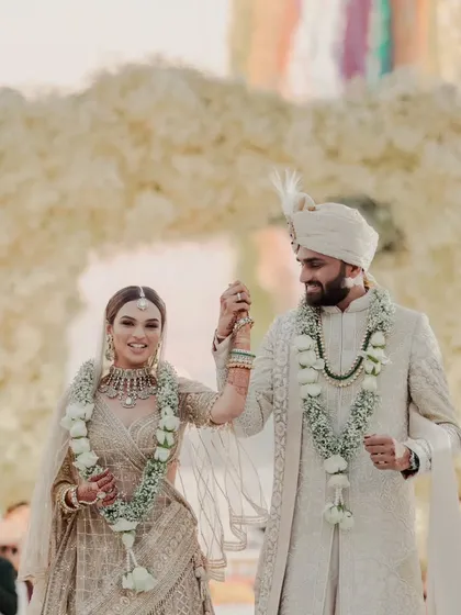 The couple walks hand in hand, all smiles after their beautiful sunset ceremony. The simple elegance of their white floral garlands complements their radiant happiness.