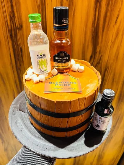 A fun barrel-shaped cake topped with miniature bottles of Blenders Pride and other spirits.
