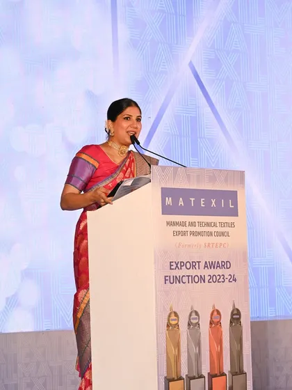 Speaking from the lectern at the Export Awards. I come prepared to represent the event's prestige, dressed appropriately in a saree to match the formal and distinguished atmosphere.