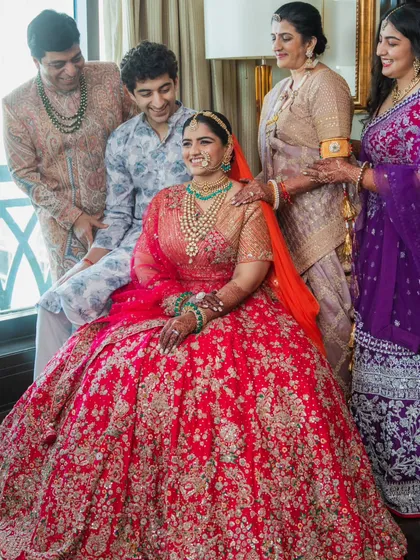 Getting the whole family together for a photo is a beautiful moment. I styled each member to complement the bride's stunning red lehenga, ensuring their outfits worked together harmoniously. It was a challenge, but seeing them all together, looking so happy, was worth it.