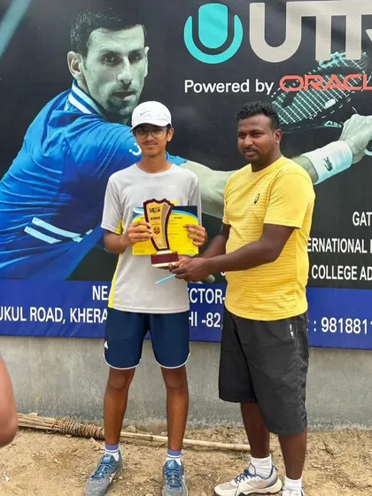 Khushank Bhushan receives his award for winning the U18 Boys' title at a UTR tournament. The backdrop features tennis legend Novak Djokovic, inspiring our young players.