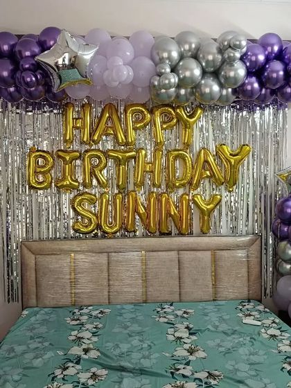 A full view of the bedroom birthday decoration for 'SUNNY', showing two balloon pillars framing the bed.