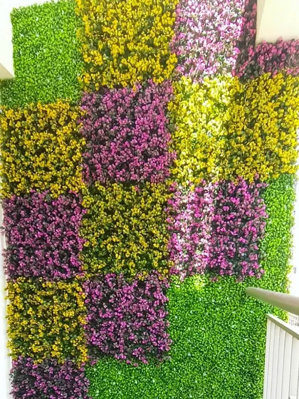 We offer full customization with a wide range of colors and textures. This balcony installation features a modern, geometric pattern using panels of green, yellow, and purple foliage to match the client's specific aesthetic.
