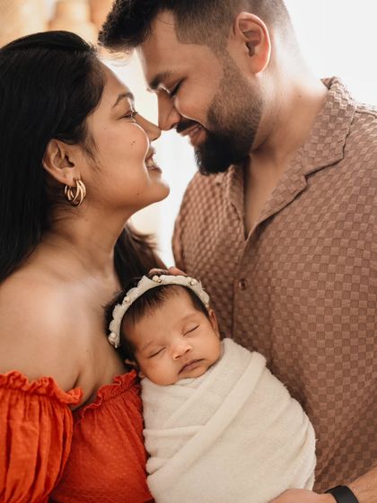 The playful, happy connection between new parents is just as important to capture. Here, their joy and love for each other shines as they hold their sleeping baby.