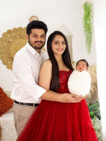 A classic first family portrait. The parents proudly hold their swaddled newborn in this bright and happy photo from my boho-themed studio.