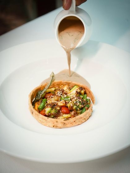 Seasonal vegetables, tossed in a fragrant tadka, are nestled in a crisp tart shell. A velvety sauce is poured over the top, creating a celebration of homestyle comfort, plated with finesse.