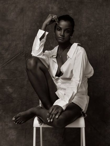 A classic black and white portrait on a stool. The composition is elegant and timeless, perfect for a model's book.