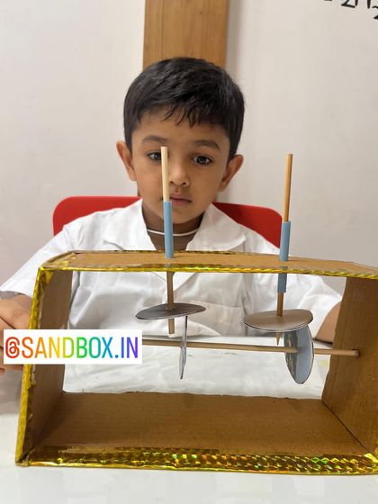 A young builder carefully assembles his simple machine. These projects help develop fine motor skills and an intuitive understanding of mechanical concepts like gears and levers.