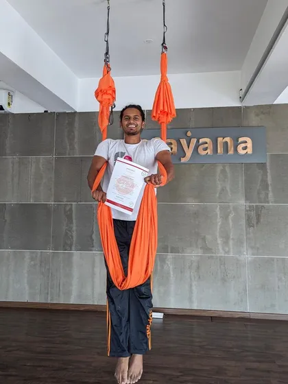 This student is all smiles as he holds his certificate, wrapped in the comfort of the aerial hammock.