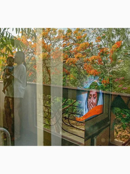 A tender moment between a parent and child is reflected against a backdrop of blooming orange flowers. This image from the series blends family life with the beauty of the natural world.