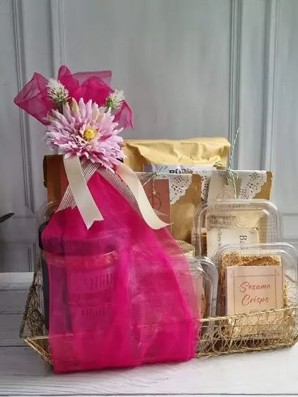 A golden mesh tray filled with a variety of our snacks and wrapped in vibrant pink. A stylish and generous gift.