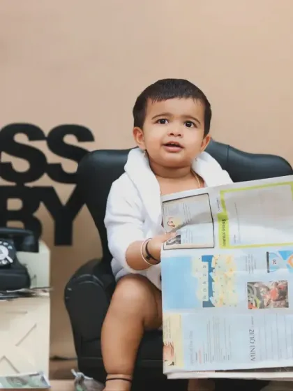 This boss baby is catching up on the daily news, sitting in his mini leather armchair with a newspaper.