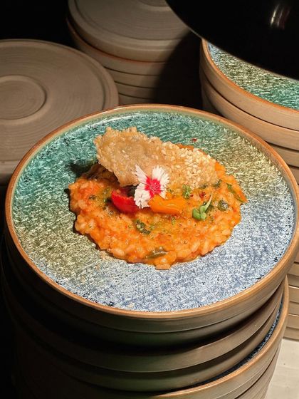 A beautifully plated risotto, garnished with an edible flower and a crispy sesame wafer. Our entrees are designed to add a touch of elegance and fusion to your palette.