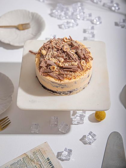 An overhead view of our Mango and Chocolate ice cream cake, showcasing the generous topping of chocolate shavings and hazelnuts.