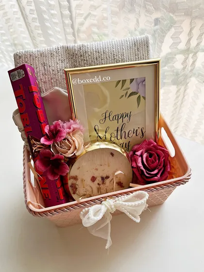 A sweet Mother's Day gift basket with a framed quote, a scented candle, chocolate, and other pampering items.