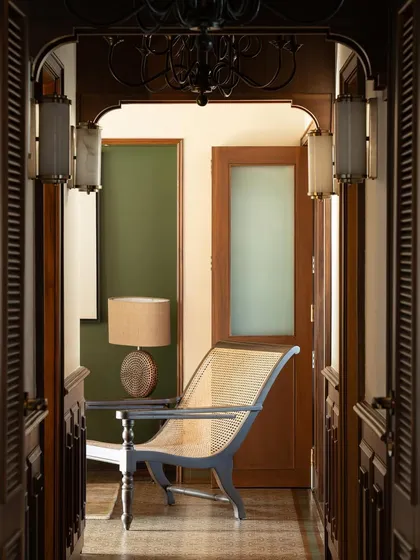A view through a doorway into the master lounge, highlighting a classic planter's chair.