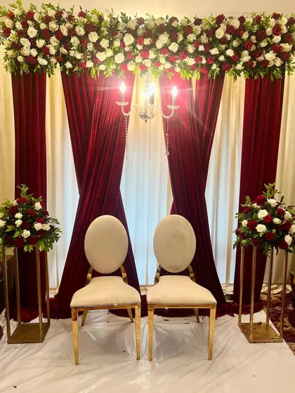An elegant Baat Pakki ceremony setup. We used rich burgundy velvet drapes, a cream backdrop, and lush arrangements of red and white roses to create a classic and sophisticated look.