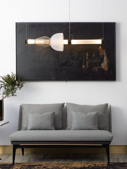 A single horizontal Luna Kaleido fixture is positioned above a settee, acting as a piece of wall art. This demonstrates the light's dual function as both an illumination source and a decorative element.