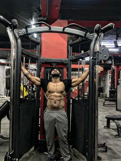 Something big is coming. A powerful pose inside the cable machine, showing off a full set of abs.