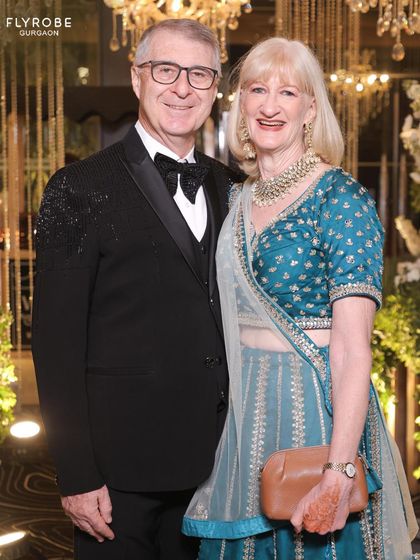 This couple shines bright as wedding guests. Her teal lehenga and his black tuxedo are a perfect blend of Indian and Western styles.