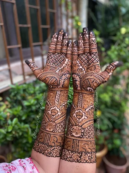 A full view of an engagement mehendi against a natural backdrop. The intricate patterns extend up the arms, creating a stunning look for the bride-to-be.