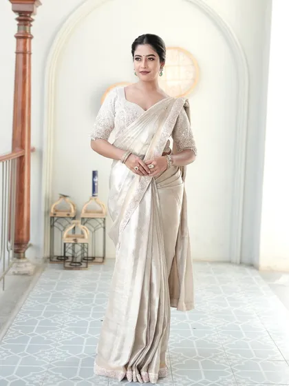 The epitome of understated elegance. This special tissue silk saree in a soft ivory is a masterpiece of light and texture. Paired with a fully hand-embroidered blouse covered in pearls and cutdana, this ensemble is crafted for the bride who desires a sophisticated and ethereal look for her reception or special event.