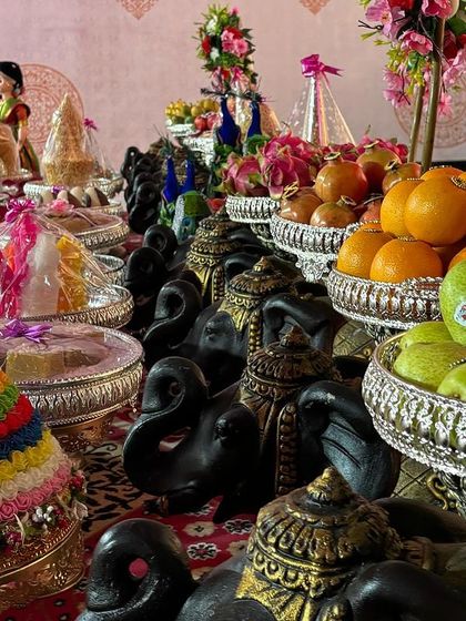 A colorful display of offerings, including a tiered doll and black elephant props.