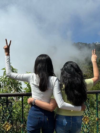Two friends making peace signs with the misty valley behind them.
