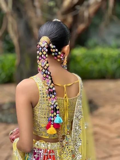 The complete look from the side. The sleek ponytail base flows into a beautifully decorated braid, creating a hairstyle that is both traditional and incredibly chic.